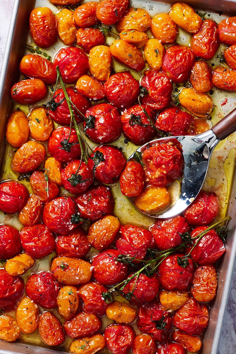 roasted tomatoes on a sheet tray with flaky sea salt and black pepper