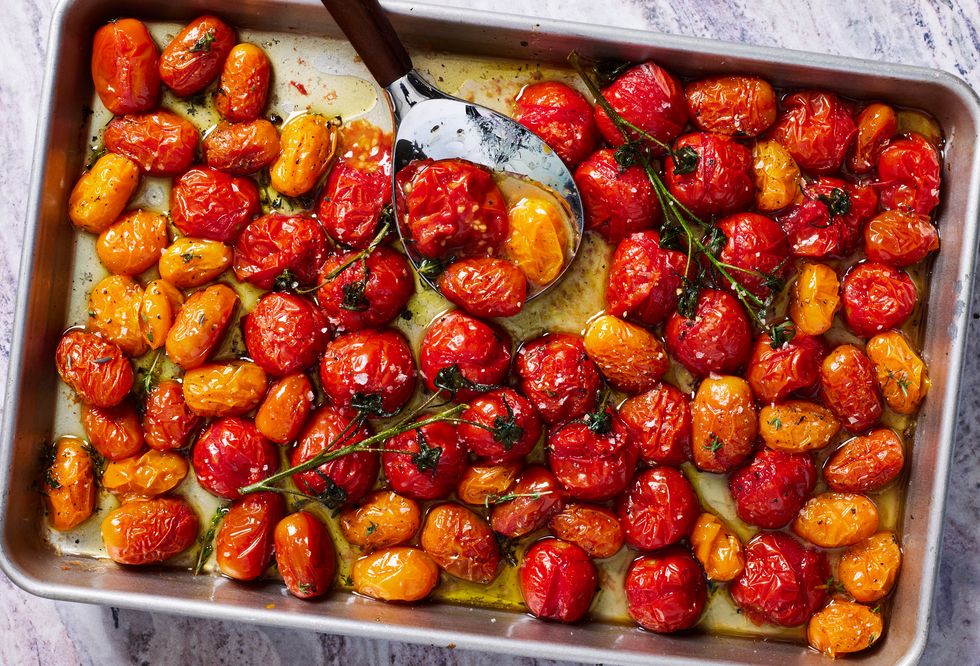 roasted tomatoes on a sheet tray with flaky sea salt and black pepper