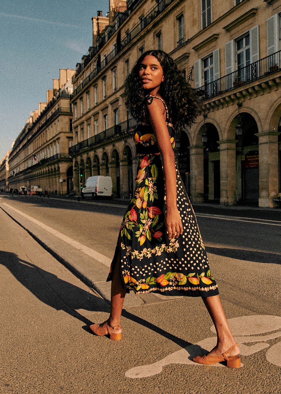a model wears a dress from sezane x farm rio while walking down a street in paris