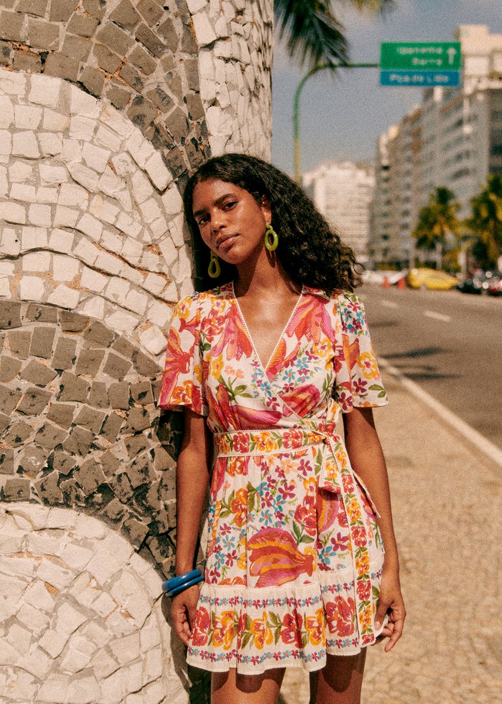 a model stands on a street in rio de jainero wearing a dress from the sezane farm rio collaboration