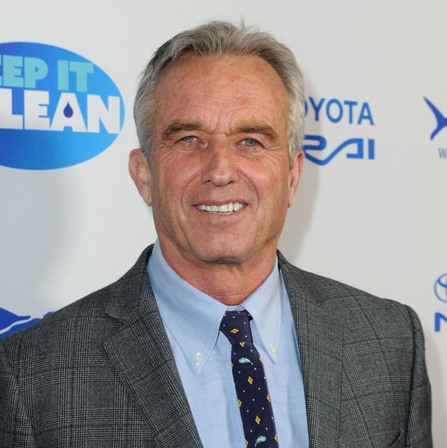 robert f kennedy jr smiles at the camera, he is wearing a gray plaid suit jacket, blue collared shirt, and blue patterned tie