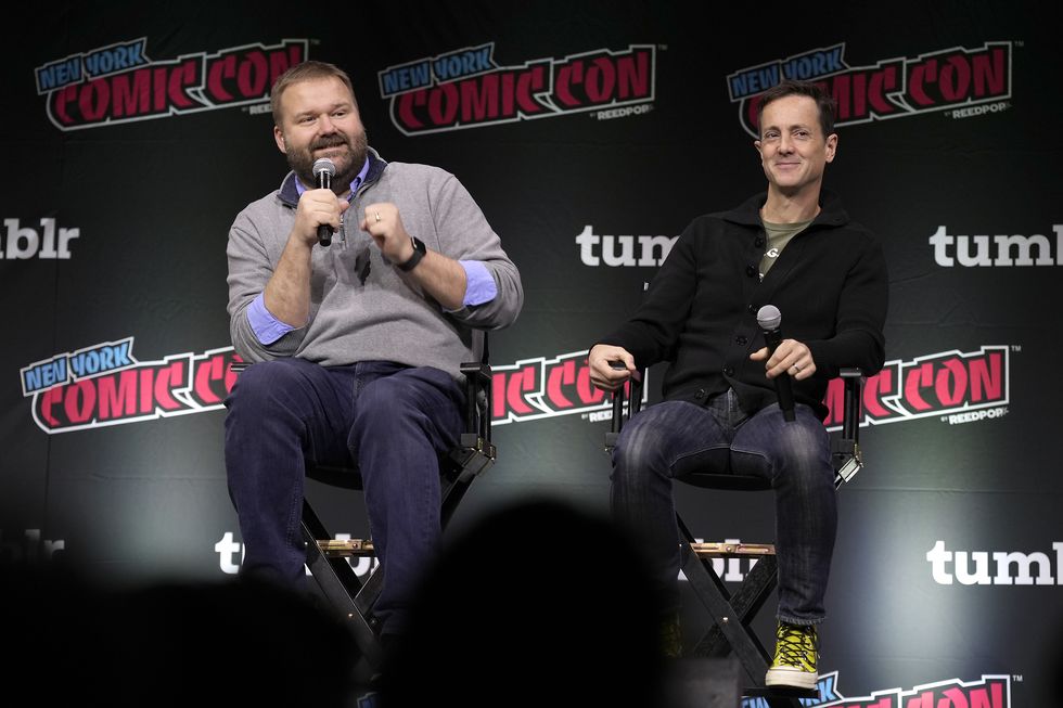 robert kirkman and simon racioppa hold microphones as they talk on stage at new york comic con