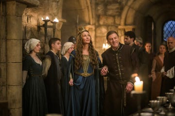 Group of characters in medieval attire interacting in a stone room