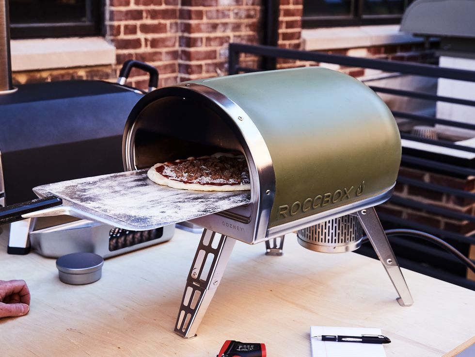 putting pizza in a roccbox pizza oven