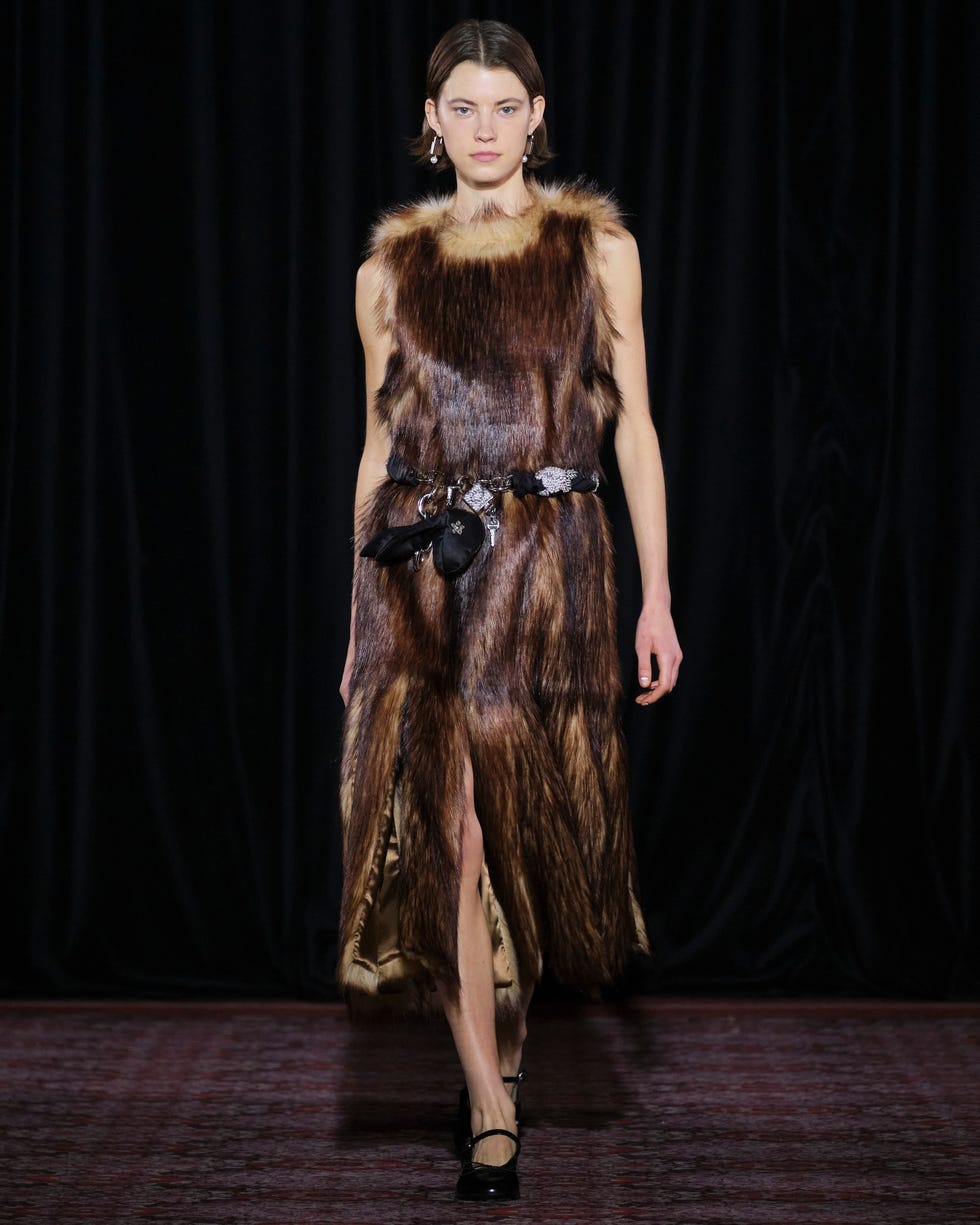 fashion model showcasing a fur dress with a slit and a decorative belt