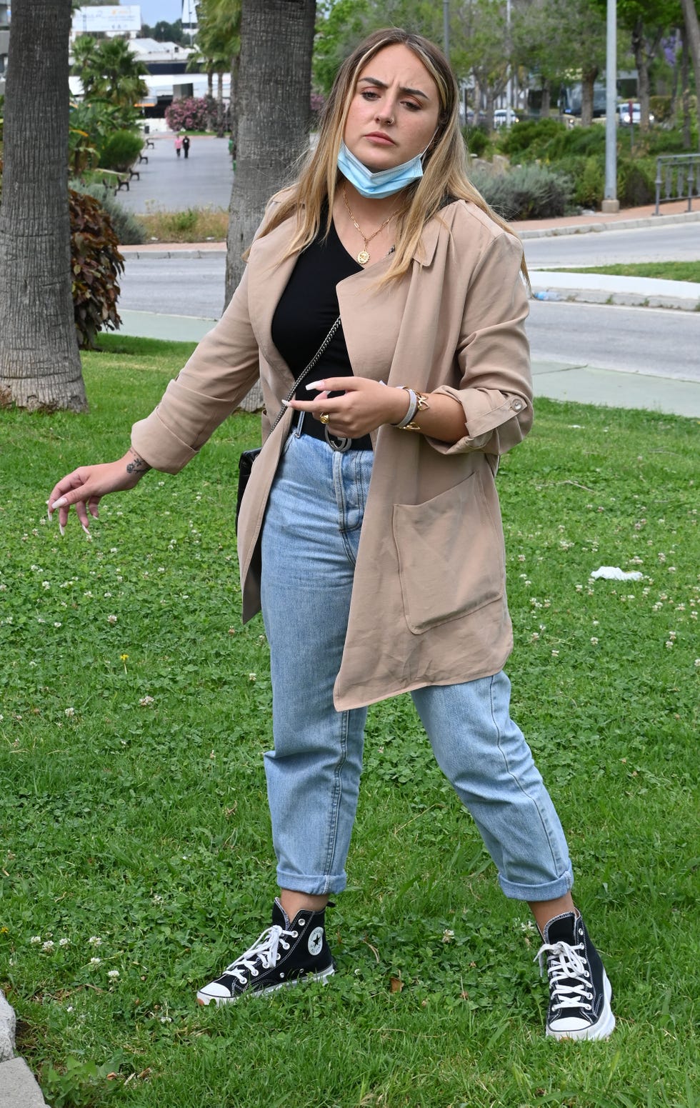 la hija de rocío carrasco, con gabardina, vaqueros y converse negras, en un jardín de la ciudad andaluza