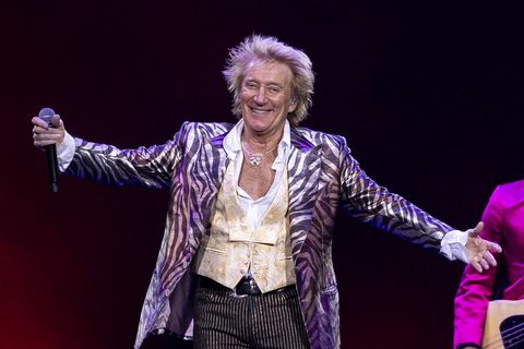 rod stewart holding a microphone and smiling during a concert