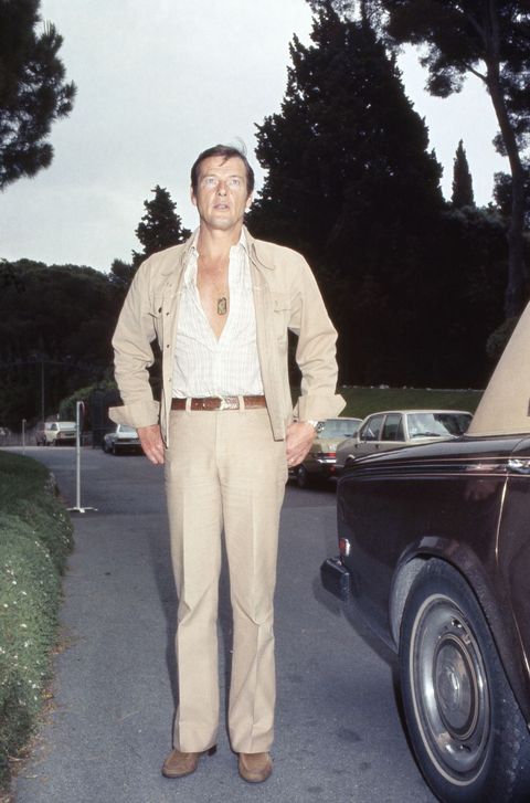 roger moore en los años 70 con pantalon y chaqueta beige y camisa abierta