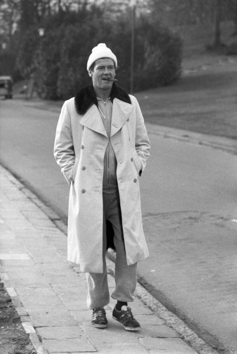 roger moore pasea en los años 70 con gabardina, chandal y zapatillas de deporte