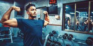 india, fitness, healthy lifestyle   indian man flexing his muscles at a gymnasium