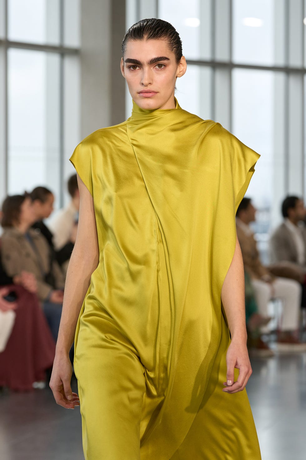 model wearing a striking yellow garment walking down a runway