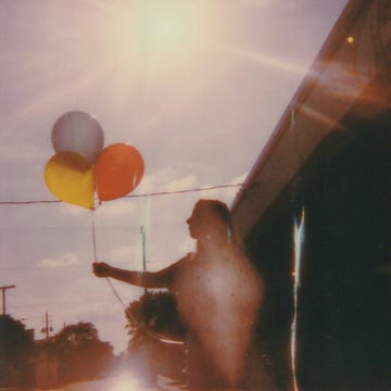 a dog looking out a window at balloons