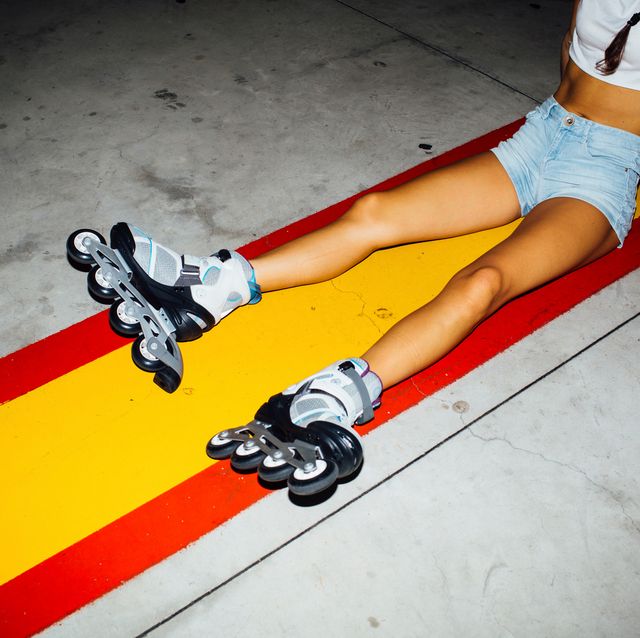 young woman with roller skates sitting on concrete