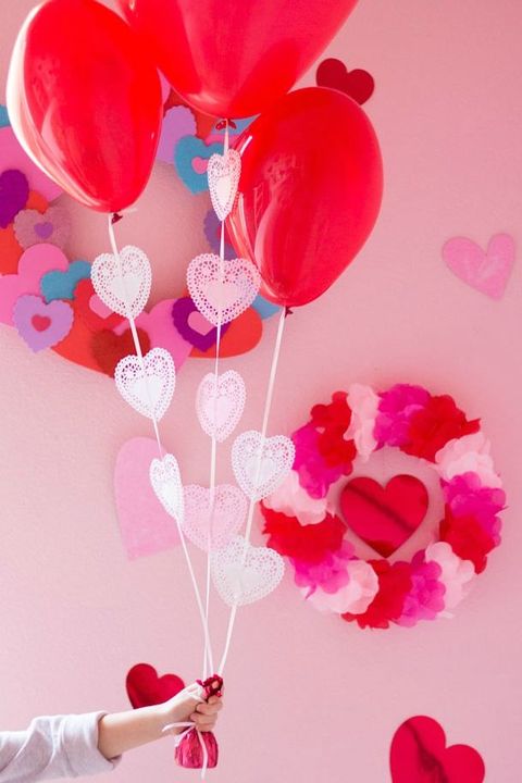 hand holding red balloons with white doilies