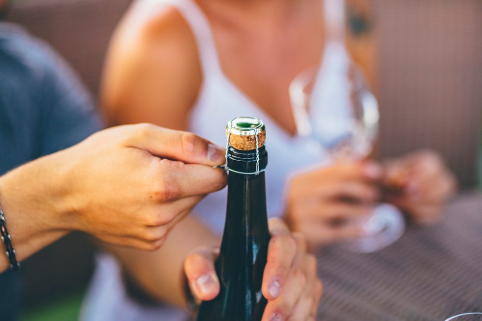 romantic couple opening a wine bottle in an outdoor party