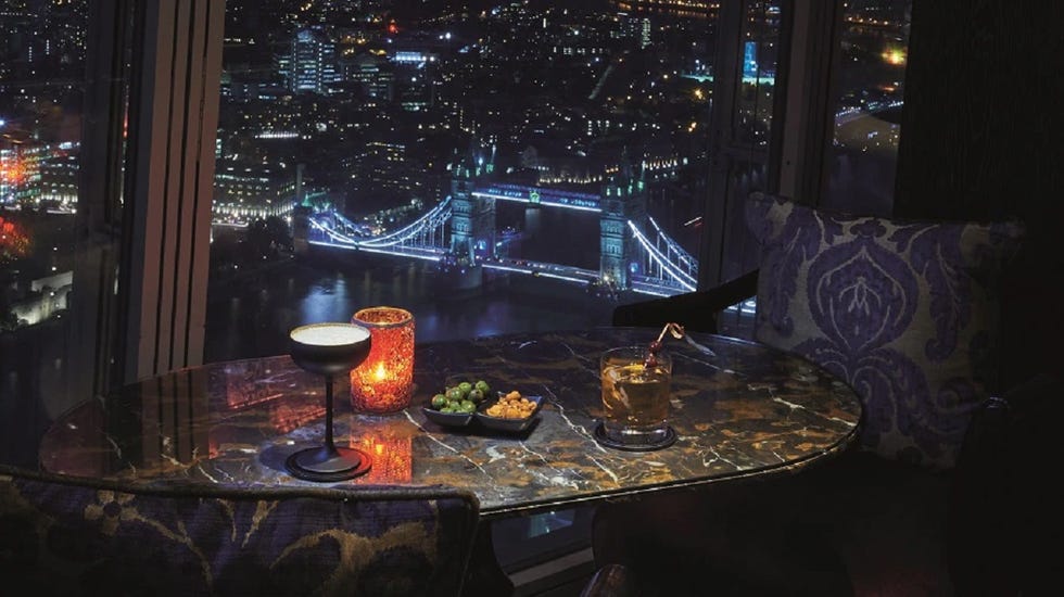 a table with food and drinks on it by a window at shangrila the shard