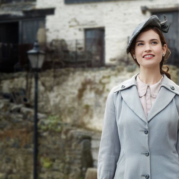 lily james walks down a lane in period garb in a scene from the guernsey literary and potato peel pie society