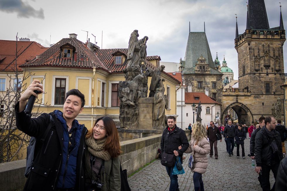 Een jong stel neemt een selfie op de Karelsbrug die de Oude Stad met de wijk Mal Strana verbindt