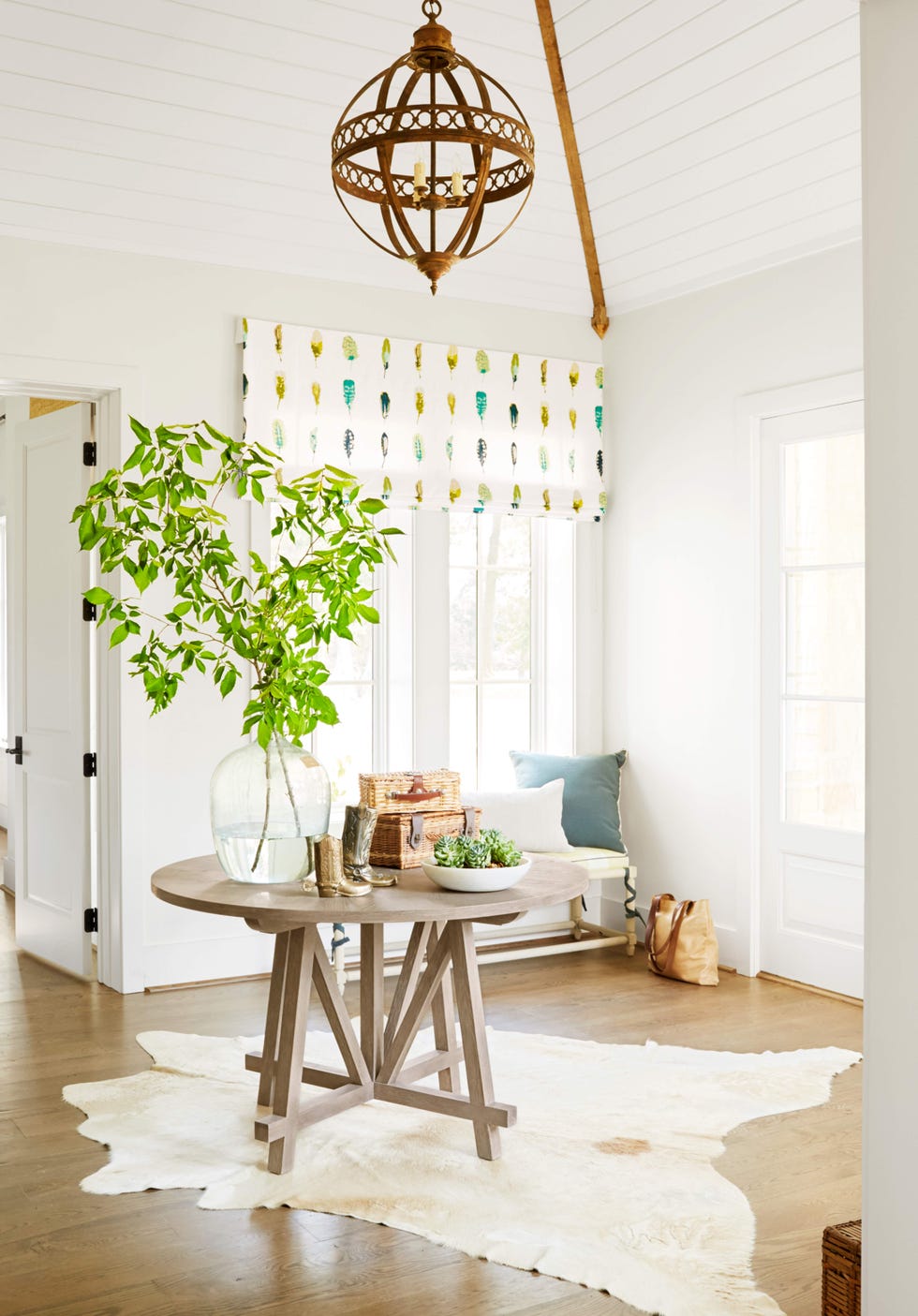 a entryway with a round pine table in the middle