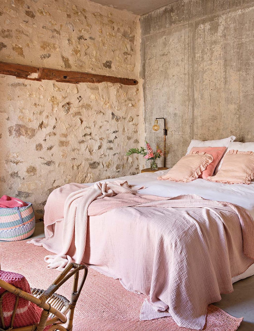 dormitorio con pared de piedra textiles en rosa