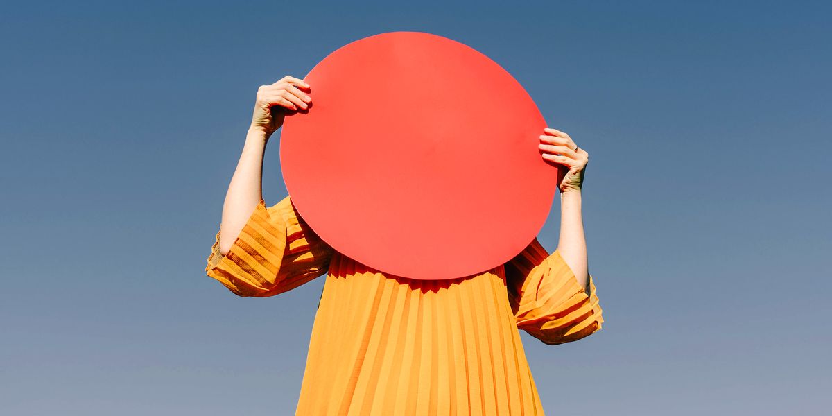 woman holding red circle over her face