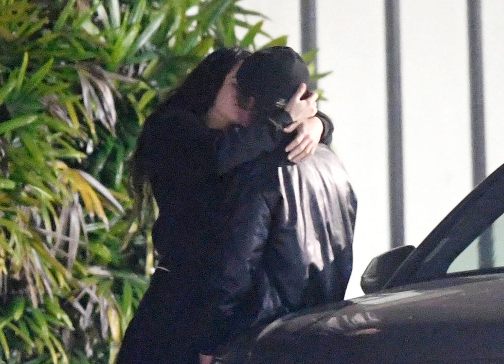 la cantante y el actor se dan un romantico beso apoyados en un coche en los angeles