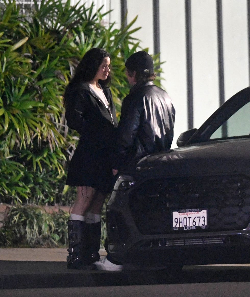 la pareja charla apoyada en un coche