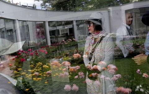 Het beeld van toeristen wordt weerkaatst in een vitrine in het Rozenmuseum dat in het Rozenpark in Kazanlak staat