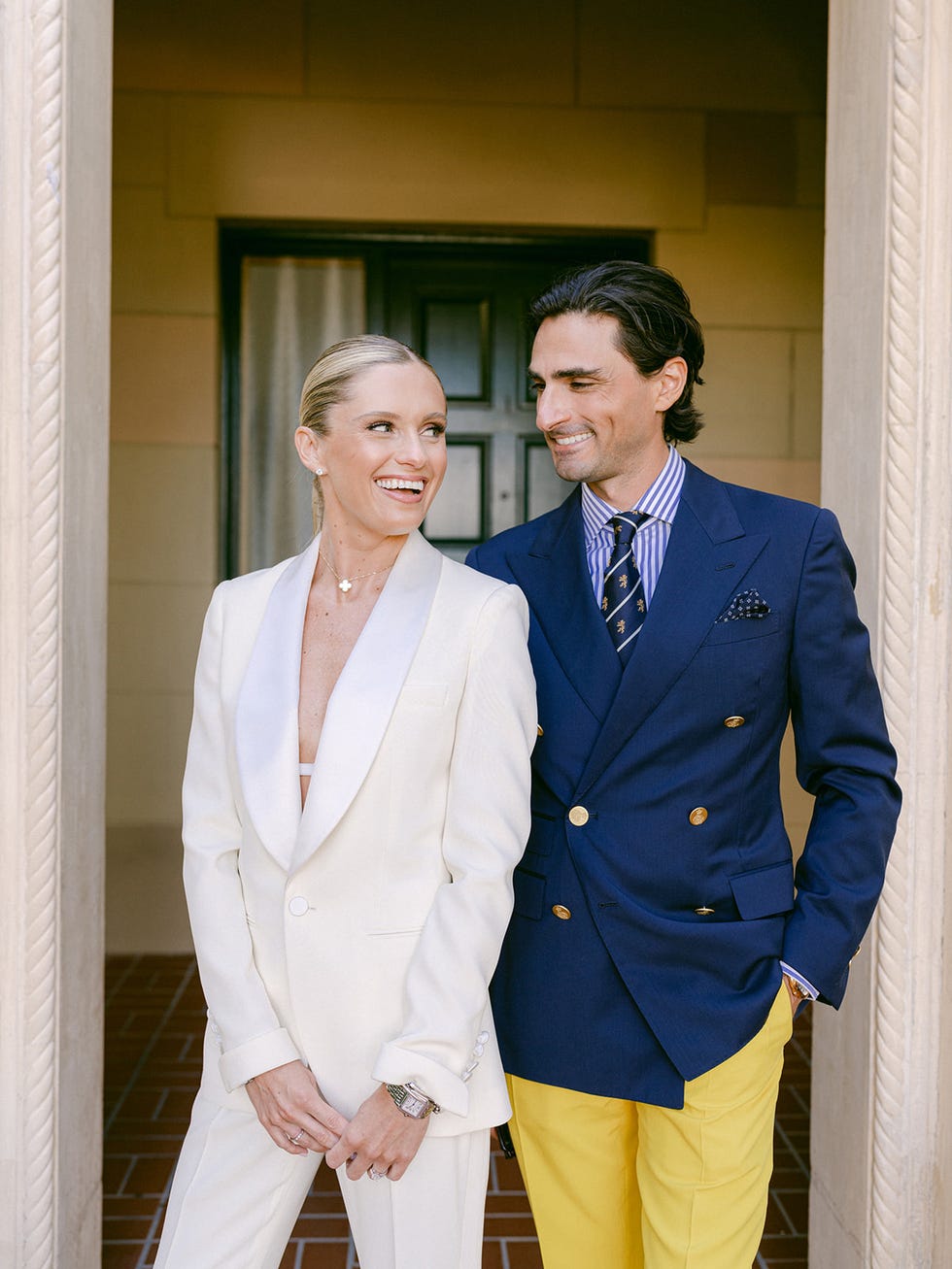 two individuals dressed in formal attire standing at an entrance