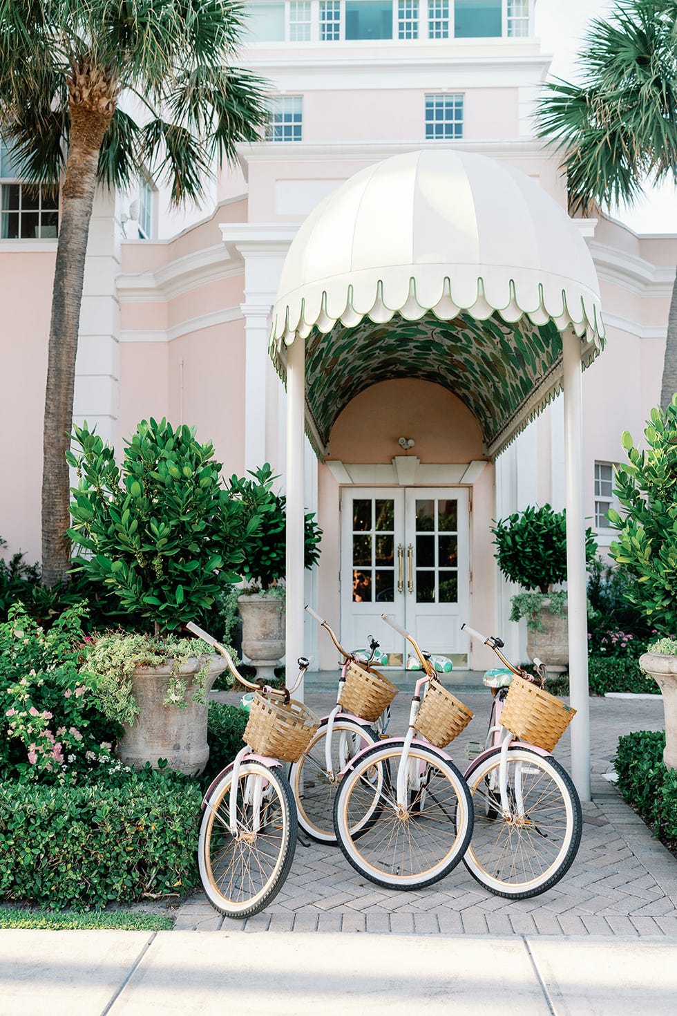 bicycles with wicker baskets parked under a canopy near a building entrance