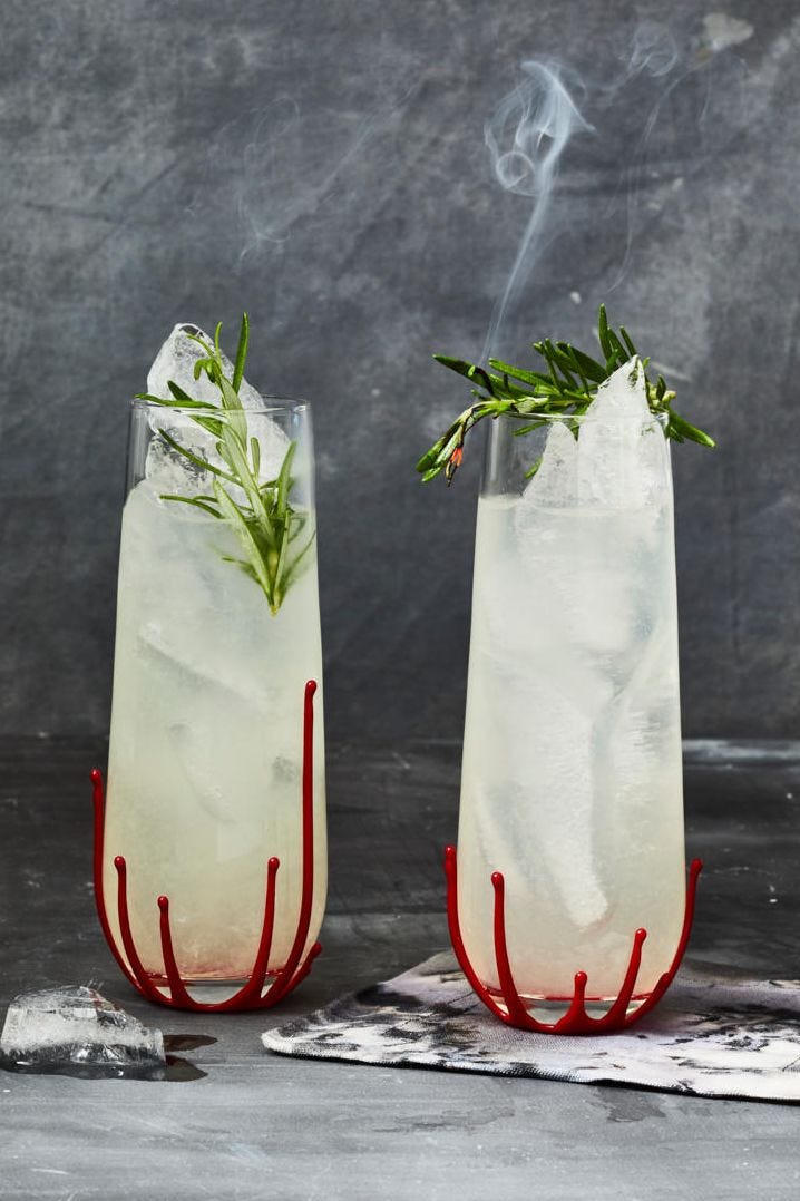rosemary gin cocktail with smoking rosemary and red candle wax on the bottom of the glass