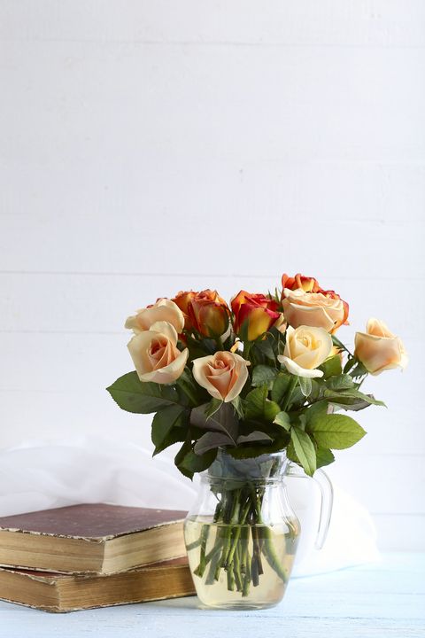 Bouquet of orange roses in vase on blue wooden background