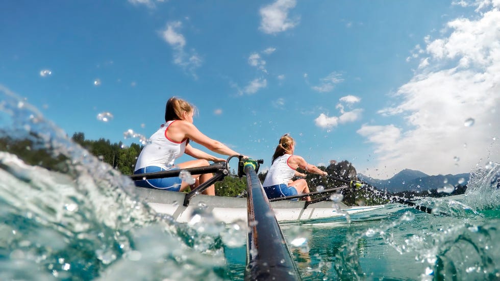 Two rowers row across the lake in the late afternoon