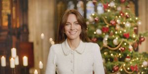 a woman smiling in front of a christmas tree