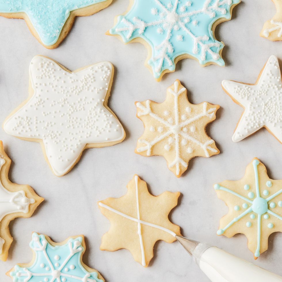 royal icing colored blue, white, and pink piped onto star and snowflake cookies