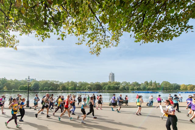 a group of people running on a road by a body of water