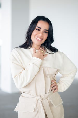 la cantante sonrie con un conjunto en color blanco