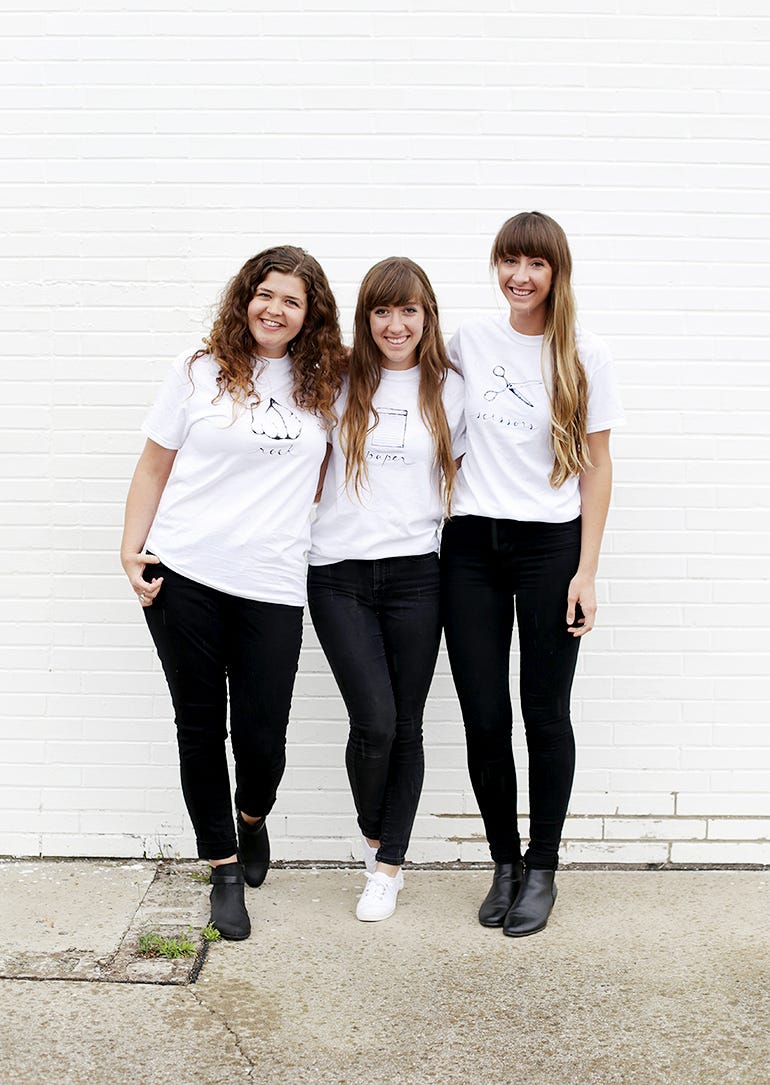 three individuals wearing matching graphic tshirts with artistic designs