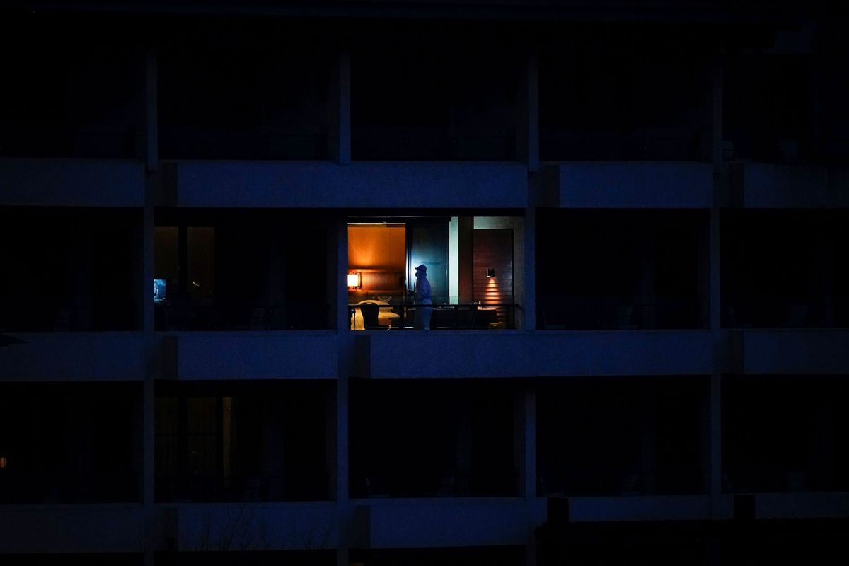 6 februari 2021 een medisch werknemer staat op het balkon van een hotel in Wuhan in China Hier verblijven de leden van het team van de Wereldgezondheidsorganisatie dat belast is met het onderzoek naar de oorsprong van COVID19