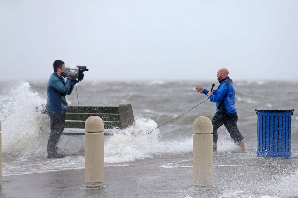 https://i.natgeofe.com/n/d007a98e-df34-48a9-a113-2cc239190a21/RTXGDV45.jpg Een nieuwsteam legt op 29 augustus 2021 de gevolgen van hurricane Ida vast terwijl het water van Lake Pontchartrain door de stormvloed over de Lakeshore Drive in New Orleans spoelt