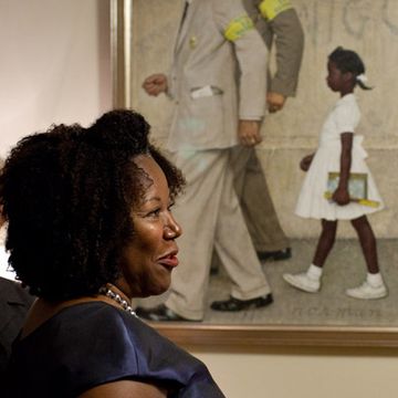 ruby bridges sitting in front of a painting in a blue dress