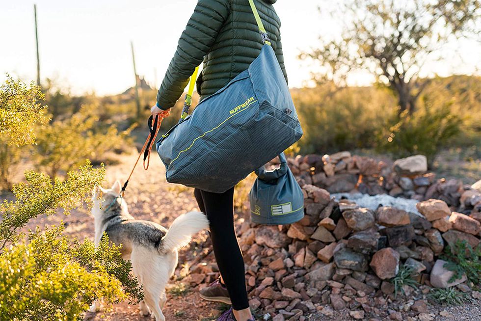 person walking dog on trail carrying ruffwear bag on his shoulder