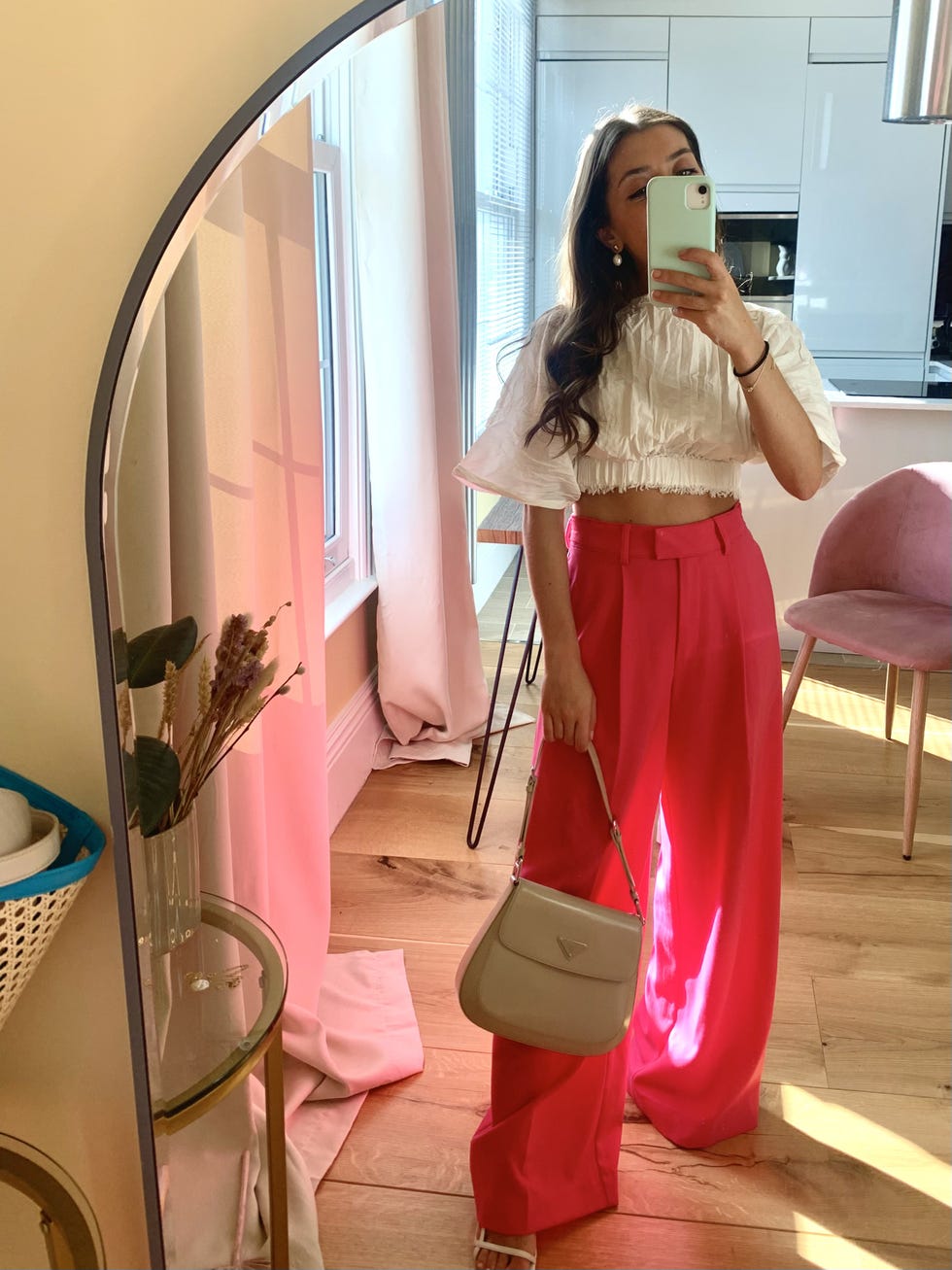 a person standing in a mirror wearing a stylish outfit in a bright room