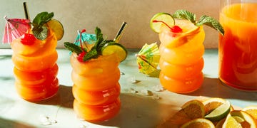 rum punch cocktail in a glass with mint, an orange slice, a lime wheel, and a maraschino cherry