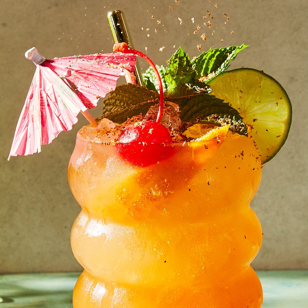 rum punch cocktail in a glass with mint, an orange slice, a lime wheel, and a maraschino cherry
