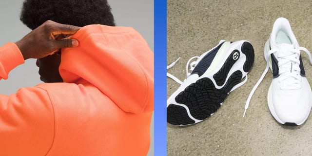 a person adjusting the hood of a bright orange sweatshirt next to a pair of white and black athletic shoes on a surface