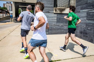 a group of guys running in running shorts on a sidewalk