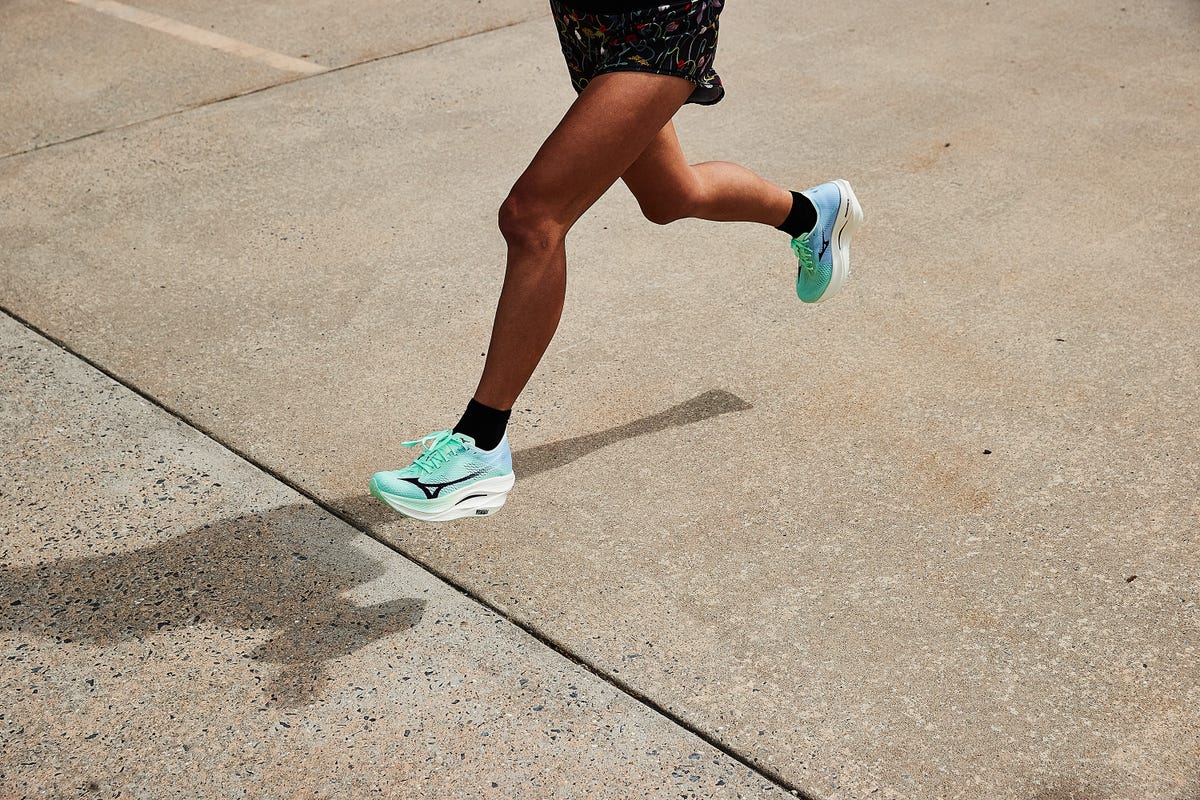 a woman running in mizuno wave rebellion pro 3 running shoes