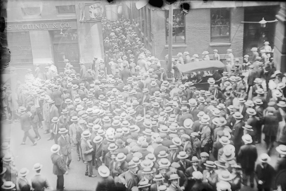 a large group of people wearing hats crowd the streets around a brick building