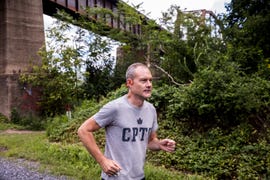 a person running on a wooded trail in shokz openrun pro headphones